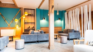A modern interior with a sofa, chairs, a wooden column, and a wall with a unique design. - Retreat With Shared Pool and Terrace (Huez)