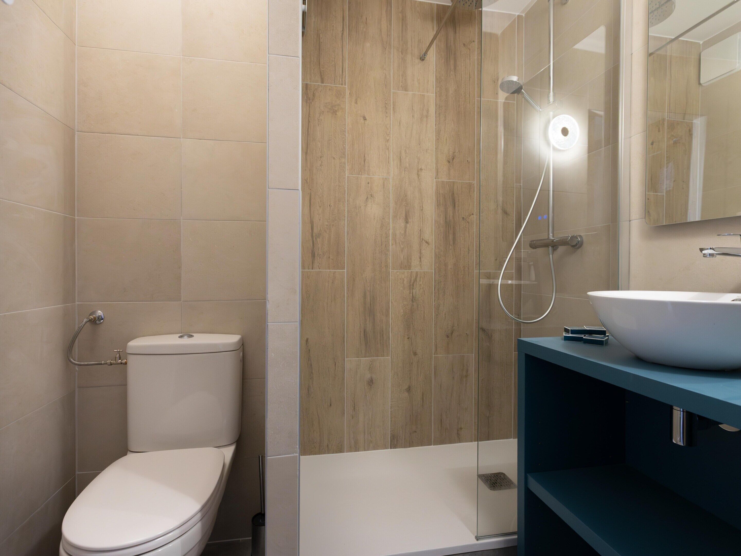 A bathroom with a toilet, a shower, and a sink.