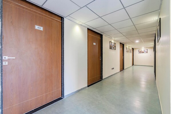 A long, narrow hallway with wooden doors and a tiled floor, leading to multiple rooms.