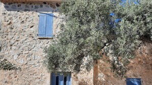 Un edificio de piedra con contraventanas azules, una puerta y una ventana.