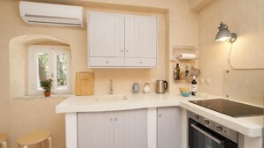 Una cocina con armarios blancos, un fregadero, una estufa y una ventana con vistas al verdor.
