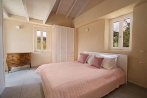 A bedroom with a bed, a dresser, a window, and a door. - MATHILAD'S HOUSE: traditional stone house in unspoiled nature (Tselendata)