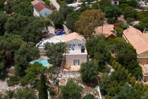 An aerial view of a residential area with houses, a swimming pool, and dense vegetation. - MATHILAD'S HOUSE: traditional stone house in unspoiled nature (Tselendata)