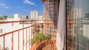 A balcony with a view of a cityscape, a curved glass structure, and a metal railing. - Saigon Maison 1988 Bui Vien Central (Ho Chi Minh City)