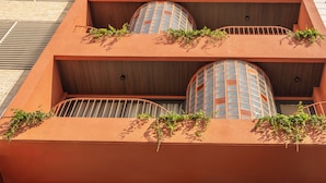 A building with a unique architectural design featuring two large cylindrical structures with a grid-like pattern, surrounded by balconies with railings and small plants. - Saigon Maison 1988 Bui Vien Central (Ho Chi Minh City)