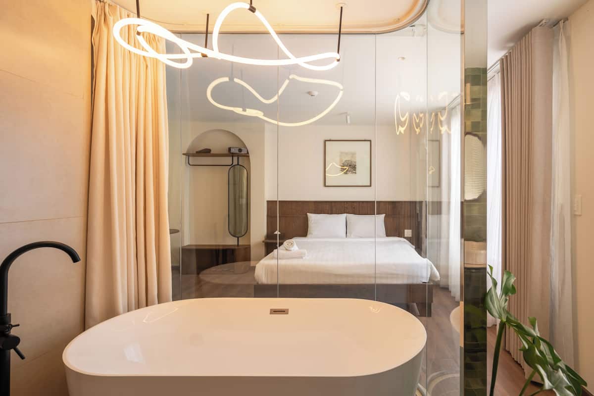 A modern bathroom with a freestanding bathtub, a shower, and a glass-enclosed bed area.