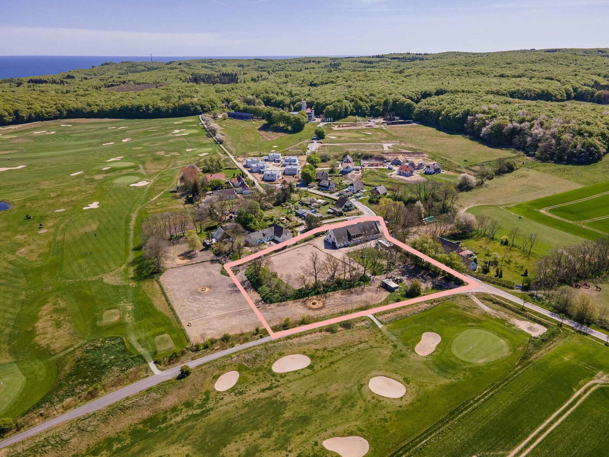 An aerial view of a golf course with multiple bunkers, a clubhouse, and residential buildings.