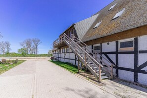 A building with a staircase leading to a second floor, a paved pathway, and a clear blue sky. - Ferien auf dem Reiterhof (Lohme)