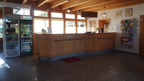 A reception area with a wooden reception desk, a vending machine, and a wall-mounted information board. - Ferienhaus im Feriendorf an der Ostsee (Klütz)
