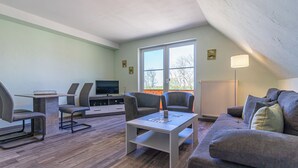 Una sala de estar con sofá, sillas, televisor, mesa de centro y lámpara.