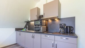 Una kitchenette compacta con microondas, tostadora y cafetera.