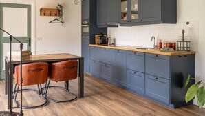A kitchen with dark blue cabinets, a wooden countertop, and a sink.