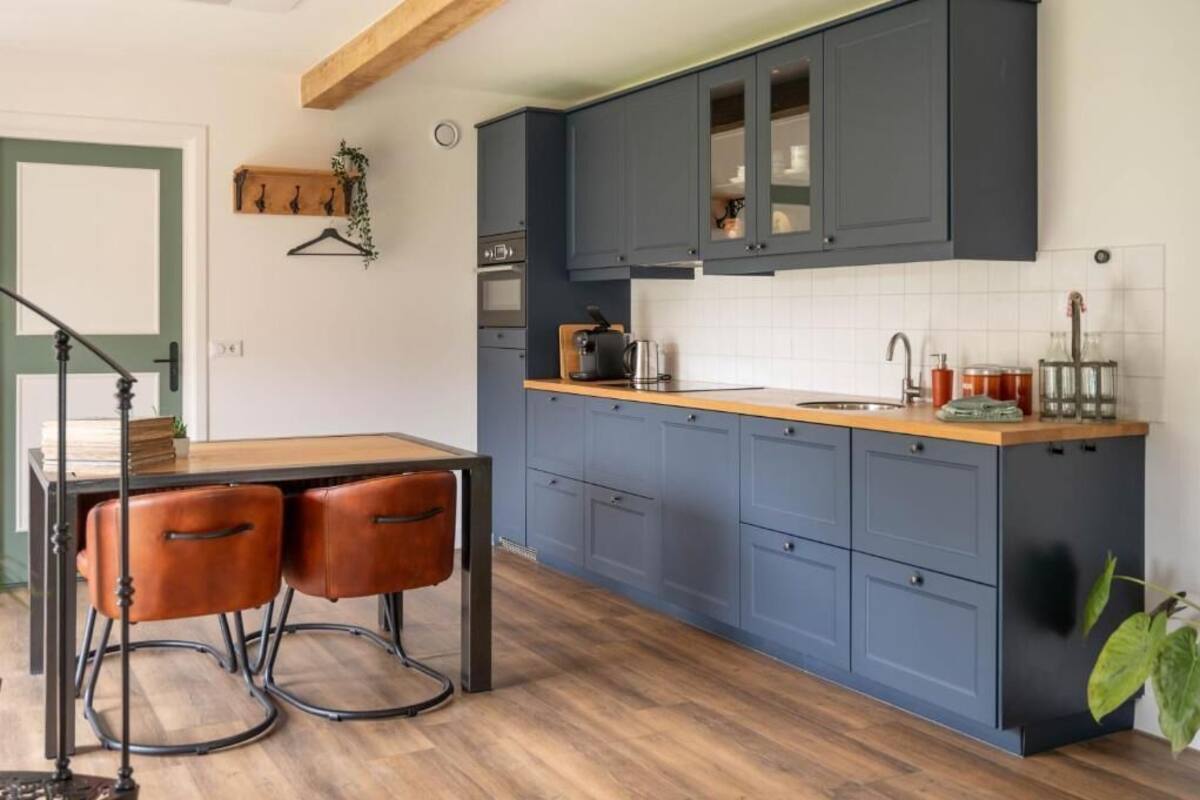 Une cuisine avec des meubles de couleur bleu foncé, un plan de travail en bois et un évier.