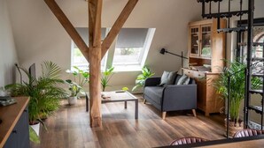 A loft-style living space with exposed wooden beams, a sofa, a coffee table, and potted plants.