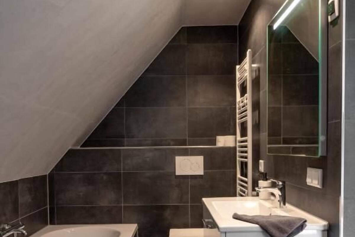 Une salle de bain moderne équipée d’une baignoire, de toilettes et d’un meuble-lavabo.