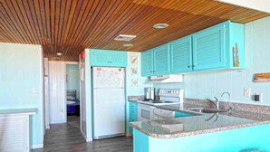 A kitchen with teal cabinets, a granite countertop, and a built-in oven. - Cute, spacious 1-bedroom oceanfront condo with free WiFi, an outdoor pool, and an expansive balcony located midtown! (Ocean City)