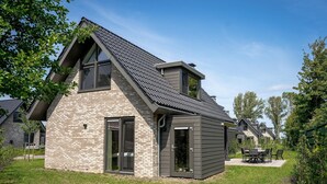 Una casa moderna con tetto spiovente, facciata in mattoni e patio con mobili da esterno.