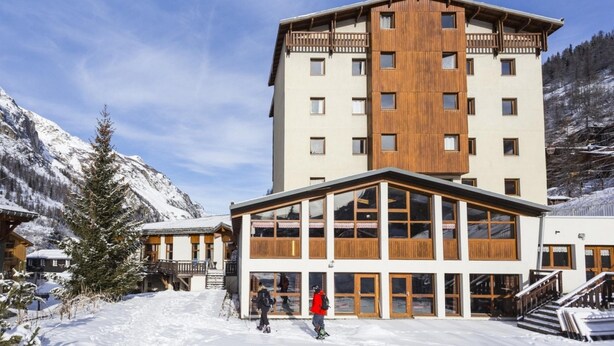 A multi-story hotel with a wooden facade, large windows, and a ski slope in the background. - Stylish Stay With Terrace & Wellness (Tignes)