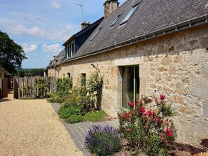 A stone building with a gravel driveway, a green door, and a small garden with flowers and shrubs. - Elegant Neulliac Holiday Home for 15 (Neulliac)