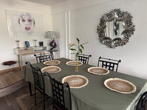 A dining area with a table set for six, surrounded by chairs, a vase with a plant, and a decorative mirror on the wall. - Spacious apartment - 6 guests. South Reunion (Le Tampon)