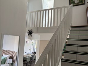 A staircase with white railings and a dining area with a table and chairs. - Spacious apartment - 6 guests. South Reunion (Le Tampon)