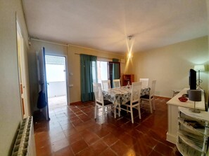 Un comedor con una mesa, sillas, un radiador y un televisor sobre un mueble.