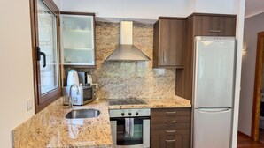 A compact kitchen with granite countertops, a built-in oven, a stainless steel refrigerator, and dark wooden cabinets. - Modern Apartment in Arinsal - 5 pers, PARKING (Arinsal)