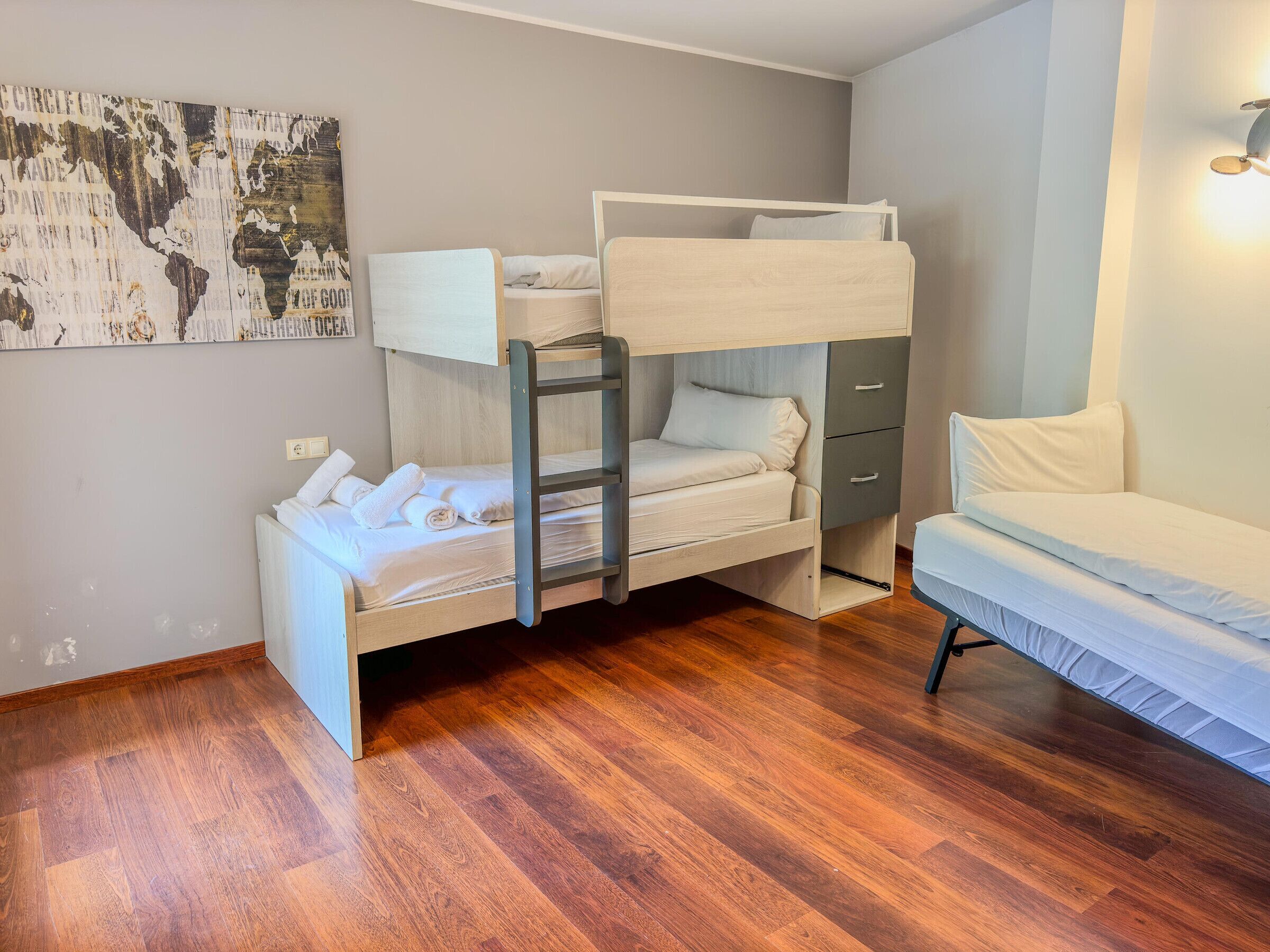 A bunk bed with a ladder, a single bed, and a small cabinet.