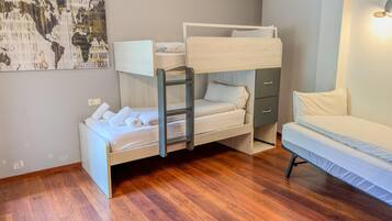 A bunk bed with a ladder, a single bed, and a small cabinet.