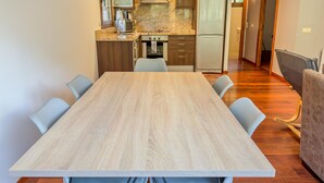 A modern kitchen with granite countertops, stainless steel appliances, and a dining area with a wooden table and chairs. - Modern Apartment in Arinsal - 5 pers, PARKING (Arinsal)