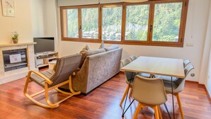 A modern living space with a sofa, a dining table with chairs, a TV, and a fireplace. - Modern Apartment in Arinsal - 5 pers, PARKING (Arinsal)