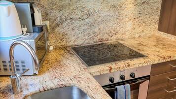 Una cocina con encimera de granito, pileta de acero inoxidable y estufa integrada.