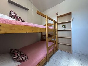 Ein Schlafzimmer mit Etagenbett, einer Holzleiter, einer rosa Matratze und einem blumigen Kopfkissen.