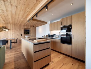 A modern kitchen with wooden cabinetry, a central island, and built-in appliances. - Modern apartment in the center - 9 guests (Montvalezan-La Rosière)