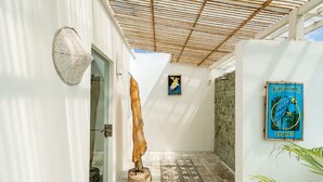 Un corridoio con soffitto in bambù, un pannello decorativo tessuto, una locandina incorniciata e un pavimento a motivi.