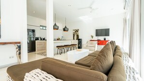 Un soggiorno moderno con un divano marrone, un tavolino bianco e una cucina sullo sfondo.