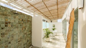 Un'area esterna riparata con doccia, piante in vaso e un angolo relax.