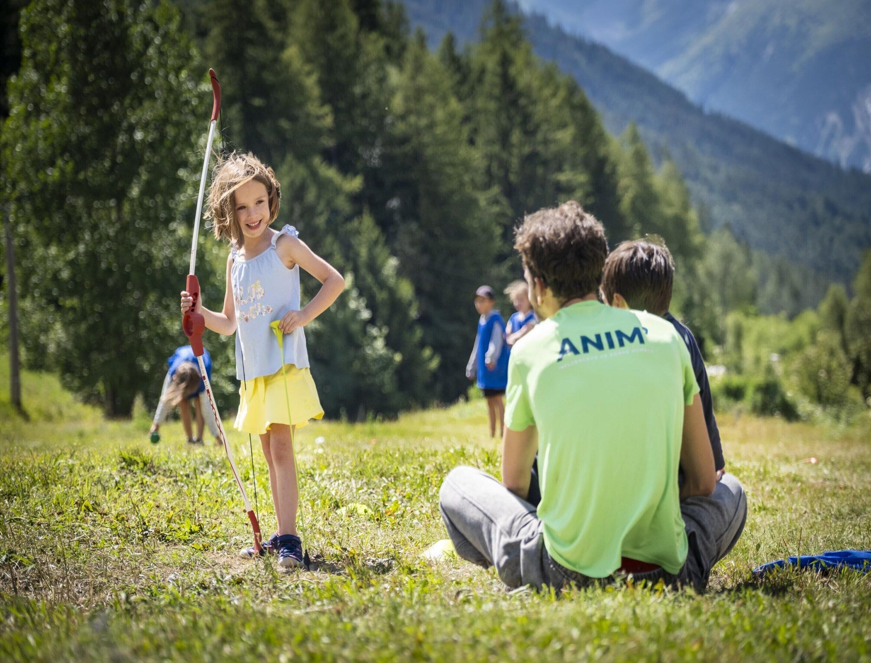 Ein grünes, offenes Gelände mit Menschen, darunter Kinder und Erwachsene, die eine Aktivität ausüben.