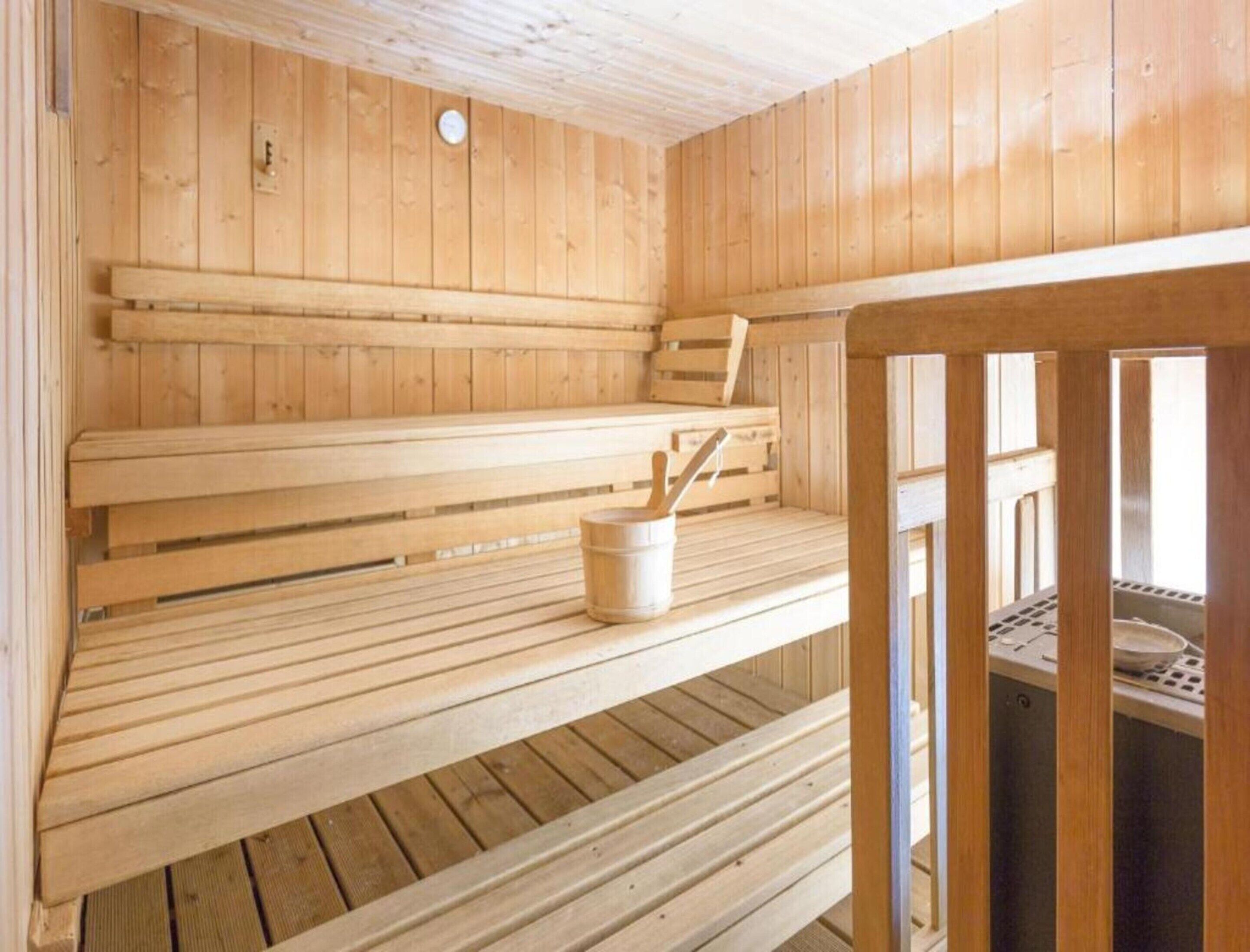 A sauna with wooden benches and a bucket.