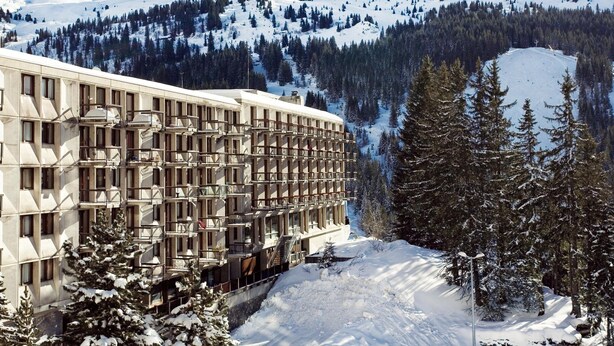 A multi-story hotel with a modern architectural design, located in a snowy mountainous area with a view of the surrounding landscape. - Stylish Alpine Base With Workspace (Araches-la-Frasse)