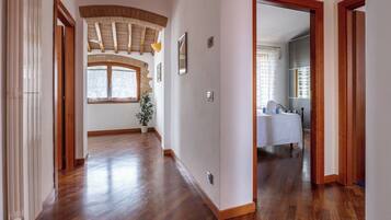 Un corridoio con pavimento in legno, una finestra con vista e una porta che conduce a una stanza con un letto e un bagno.