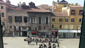 Une place en plein air, avec des bâtiments, un café et des passants.