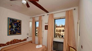 Une chambre à coucher avec un lit, une chaise, un radiateur et une fenêtre avec des rideaux.