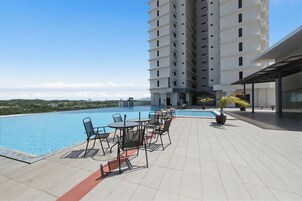 Zona de piscina en la azotea con mobiliario exterior y vistas a un edificio de gran altura.