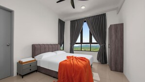 Ein Schlafzimmer mit Bett, Nachttisch, einem Fenster mit Vorhängen, einem Kleiderschrank und Blick auf die Landschaft.