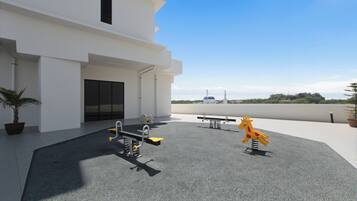 A rooftop with exercise equipment, a potted plant, and a building in the background.