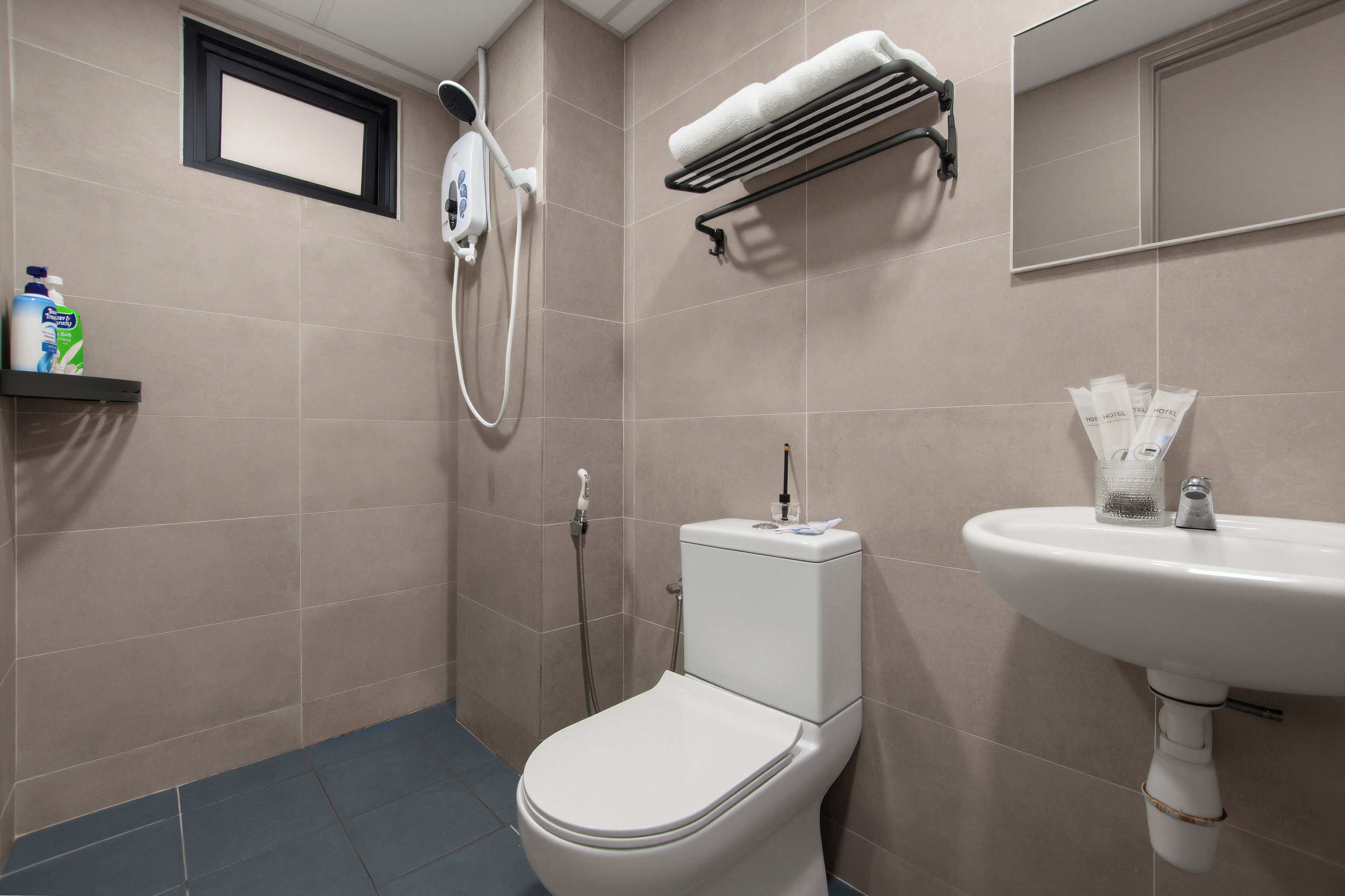 Une salle de bain moderne équipée d’un WC, d’un lavabo, d’une douchette et d’un porte-serviettes.