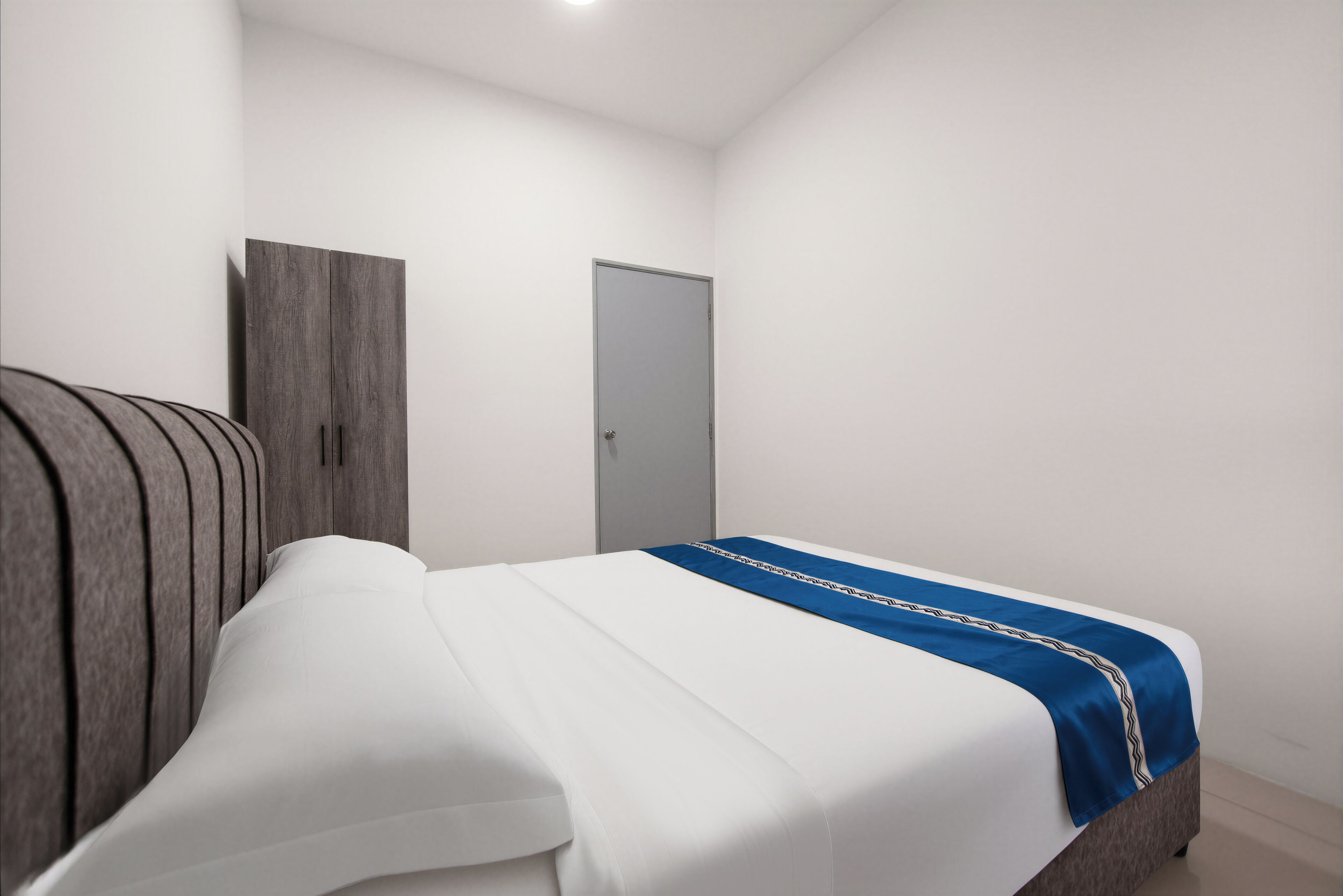 A bedroom with a bed, a wardrobe, and a door.