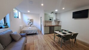 Um espaço compacto para vivenciar, com cama, área de refeições, cozinha compacta e televisão presa à parede.
