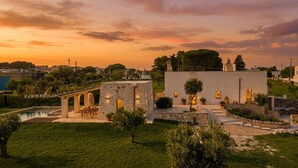 Une villa dotée d’une piscine, d’une architecture en pierre et offrant une vue sur le coucher de soleil.